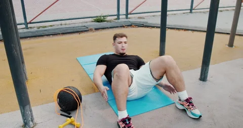 A Young Man Engaging in an Exercise Routine with a Medicine Ball and Resistance Stock Footage 318073530