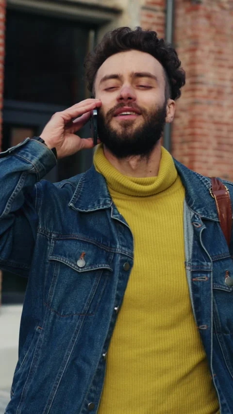 A young man is engaging with his smartphone while enjoying the vibrant urban Stock Footage 314365071