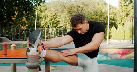 A Young Man Engaging in Stretching Exercises in an Outdoor Gym Setting Stock Footage 317837726