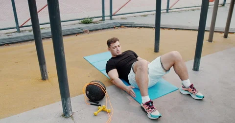 A Young Man Engaging in a Workout Routine on a Mat in an Outdoor Setting Under Stock Footage 317980845