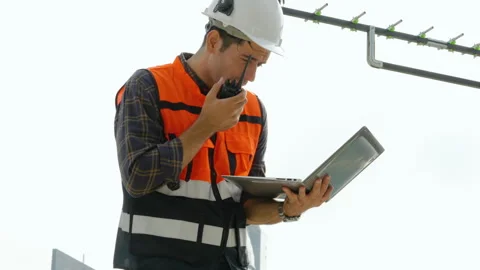 Young man engineer checking information from laptop and talking on radio call Stock Footage 280490044