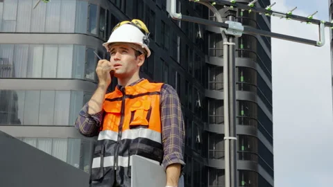 Young man engineer checking information from laptop and talking on radio call Stock Footage 280490180