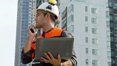 Young man engineer checking information from laptop and talking on radio call Stock Footage 280491761