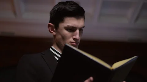 Young man is engrossed in a captivating book while seated in a sophisticated Stock Footage 291542813