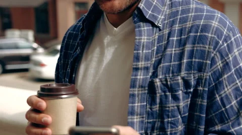 Young man enjoying coffee break while using his smartphone outdoors Stock Footage 62627989