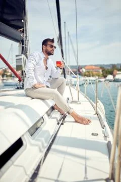 A young man is enjoying a coffee while sitting on a yacht at sea. Summer, sea Stock Photos