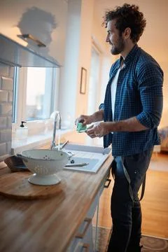 Young man enjoying doing housework in the kitchen. Kitchen, housework, quaran Stock Photos
