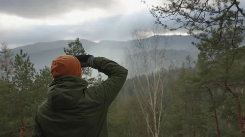 Young man enjoys the beautiful view of mountain valley on the mountain top Stock Footage 232302025