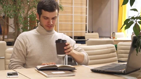 Young man enjoys coffee while working in a modern hub Stock-Footage 311981183