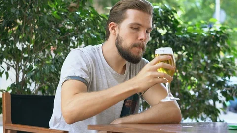 Young man enjoys drinking beer outdoors Stock Footage 125657797