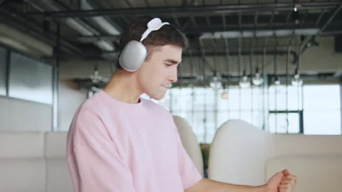 Young man enjoys music while dancing in a modern workspace during the day Stock Footage 330690657