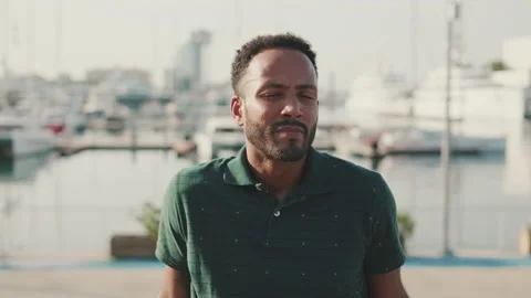 Young man enjoys relaxing while sitting in the harbor with yachts on the Stock Footage 227091364