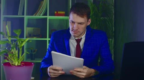 Young man examines documents, sitting in office. Serious businessman checks Stock Photos