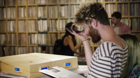 Young man examining a vinyl record for defects in music store Stock Footage 58581983