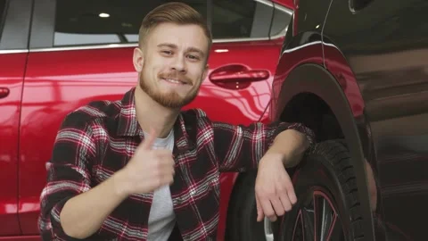 Young man examining wheels and tires of a new car at the dealership Stock Footage 311937760