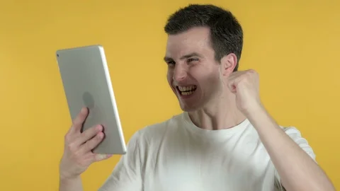 Young Man Excited for Success while Using Tablet Isolated on Yellow Background Stock Footage 112977697