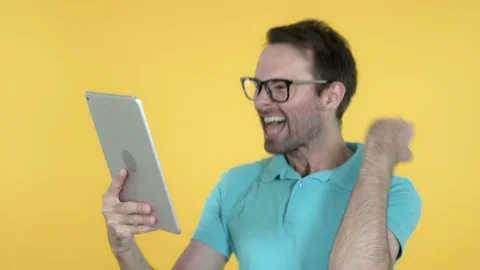 Young Man Excited for Success while Using Tablet Isolated on Yellow Background Stock Footage 113236033