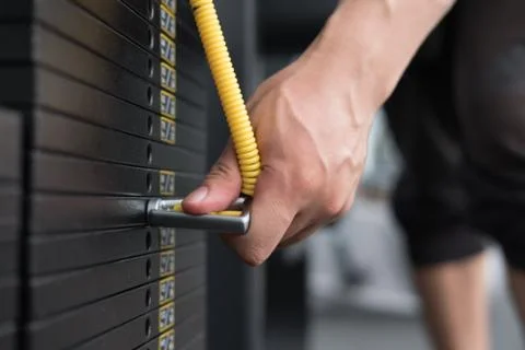 Young man execute exercise with pull down machine in fitness center. male ath Stock Photos
