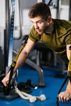 Young man exercise trx workout in gym Stock Photos