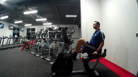 Young man exercises in the gym on an exercise bike Stock Footage 56774444