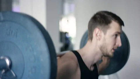 Young man exercising with barbell behind his back in a gym Stock Footage 105879873