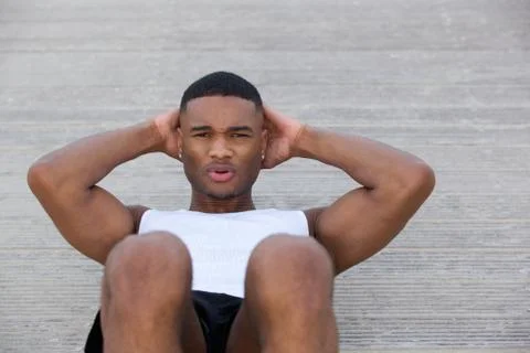 Young man exercising doing sit ups outside Stock Photos