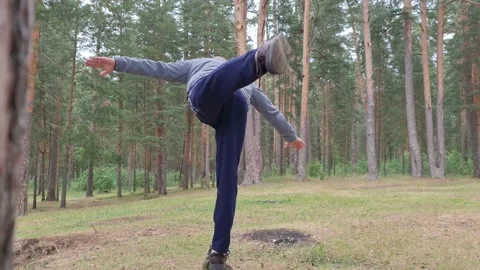 A young man is exercising in the forest. Warming up and stretching the muscles. Stock Footage 156674761