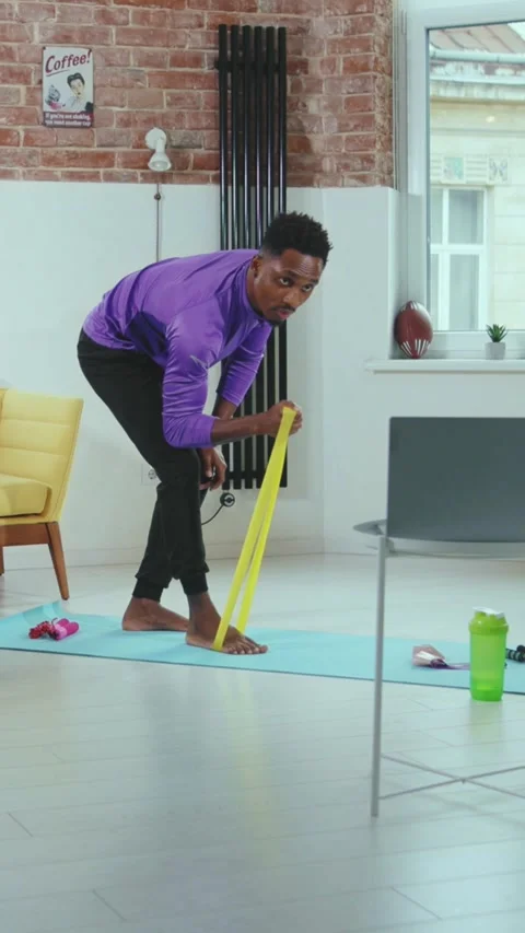 A young man is exercising at home using a resistance band for fitness and health Stock Footage 316523433