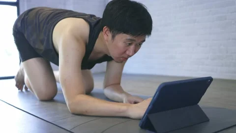 Young man exercising at home while watching a video tutorial on tablet. Male Stockbeeldmateriaal 154209247