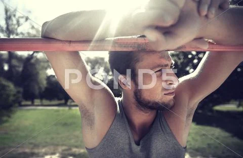 Young man exercising on horizontal bar outdoors Stock Photos