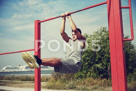 Young man exercising on horizontal bar outdoors Stock Photos