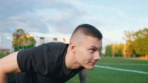 Young man exercising outdoors, does push-ups on the push-up platform at stadium Video stock 260829411