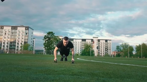 Young man exercising outdoors, does push-ups on the push-up platform at stadium Video stock 260829455
