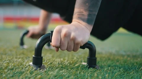 Young man exercising outdoors, does push-ups on the push-up platform at stadium Video stock 260829521
