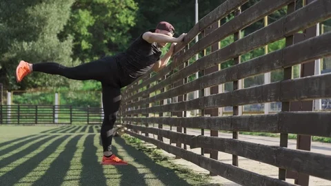 Young man exercising outdoors. Runner man warming up and stretching legs Video stock 115029956