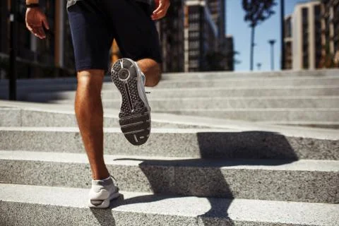 Young man exercising outside. Back low view of strong male's legs, calfs and Stock Photos