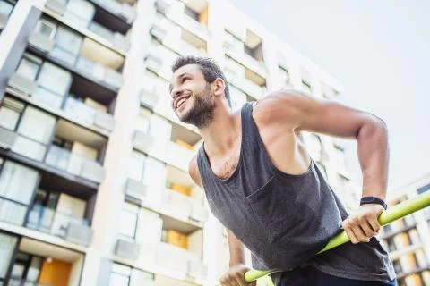 Young man exercising outside. Cheerful positive sportsman holding hands on Stock Photos