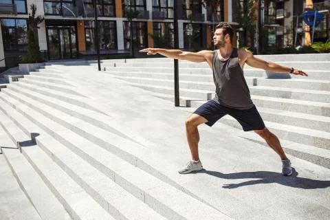 Young man exercising outside. Guy standing in yoga position alone at steps and Stock Photos