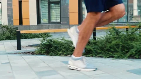 Young man exercising outside. Side view of active male's legs running or jogging Stock Footage 136433401