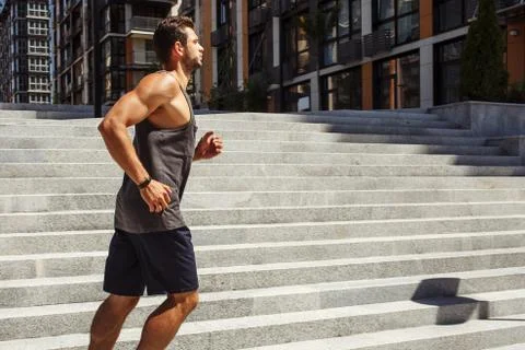 Young man exercising outside. Side view in motion of strong muscled guy running Stock Photos