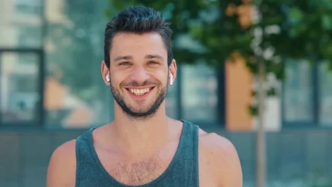 Young man exercising outside. Slow motion video portrait of guy with cheerful Stock Footage 136408034