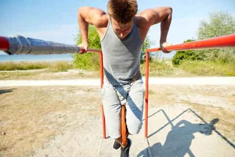 Young man exercising on parallel bars outdoors Stock Photos