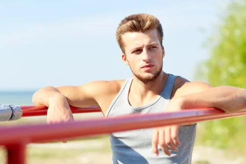Young man exercising on parallel bars outdoors Stock Photos