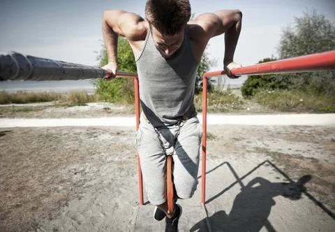 Young man exercising on parallel bars outdoors Stock Photos