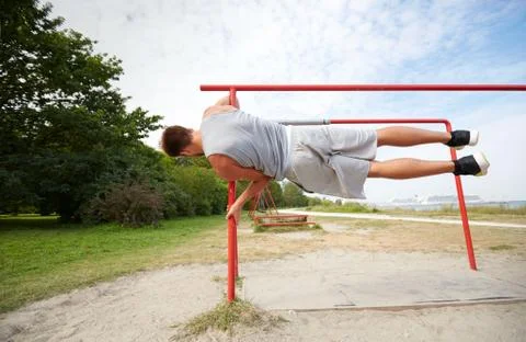 Young man exercising on parallel bars outdoors Stock Photos