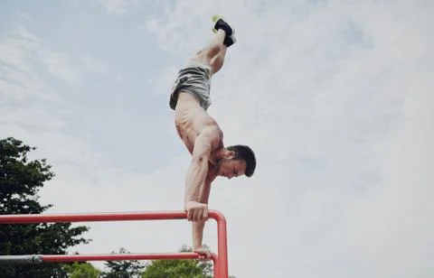 Young man exercising on parallel bars outdoors Stock Photos