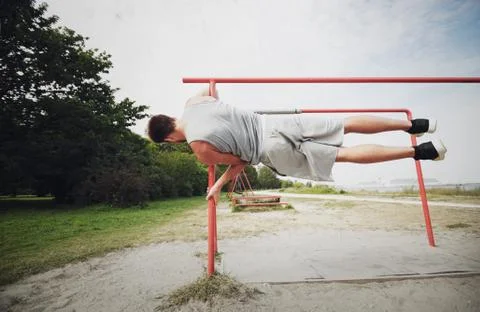 Young man exercising on parallel bars outdoors Stock-Fotos