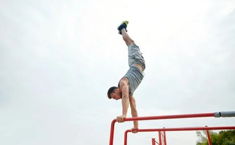 Young man exercising on parallel bars outdoors Foto stock
