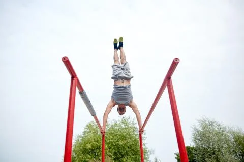 Young man exercising on parallel bars outdoors Stock Photos