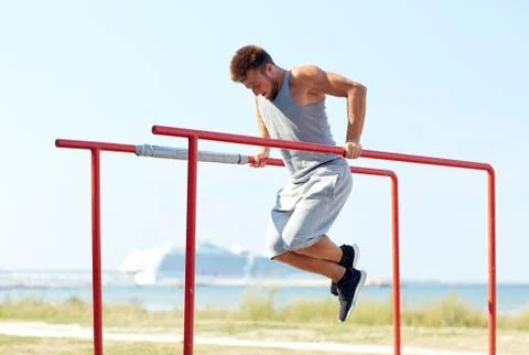 Young man exercising on parallel bars outdoors Stock Photos